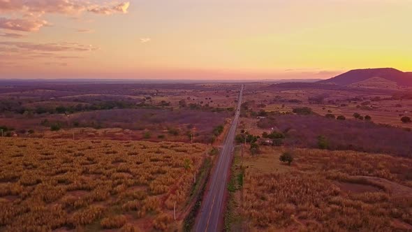 Aerial landscape view of barren fields and a single road passing through rural Bahia at dusk