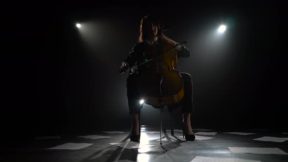 Scattered Notes on the Floor and the Silhouette of a Musician with a Cello in a Dark Studio