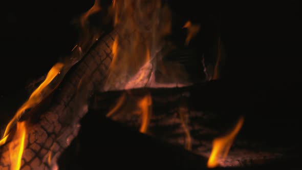 Burning logs in fire pit outside at night time. Slow Motion. Unedited version included.