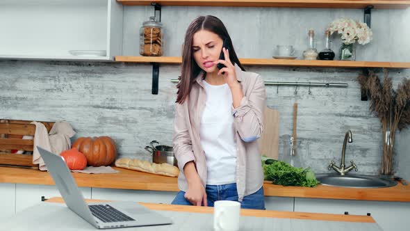 Angry Casual Female Talking Using Smartphone in Kitchen at Home Having Negative Emotion