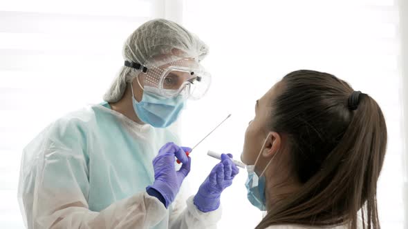 Nurse in a protective suit takes a nasal swab sample from a young patien