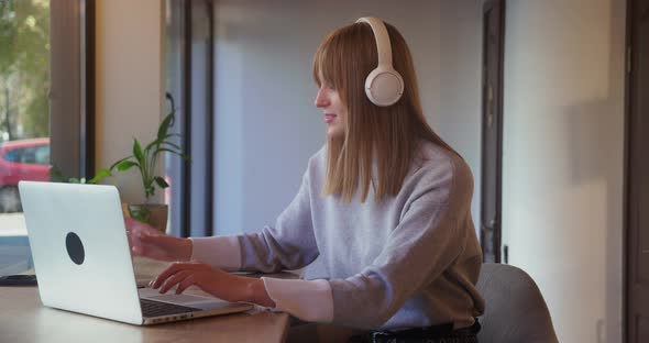 Female Young Worker Using Laptop in Coworking Space or Cafe and Drinking Tea