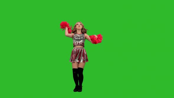 An Adorable Cheerleader in Uniform with Red Pompoms Performs a Jubilant Dance