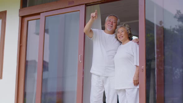 Happiness Two Asian couple elder with white hairs standing beside windows together and looking bird
