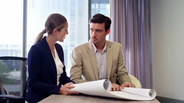 Businesswoman and businessman discussing over a blueprint