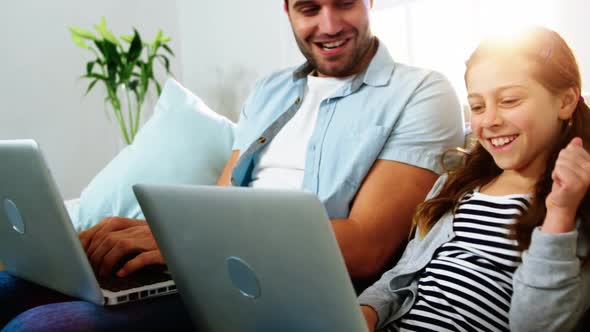 Father and daughter using laptop in the living room