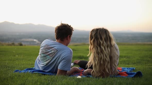 Shot of cute boyfriend and girlfriend laying on a blanket and having a picnic on the grass.