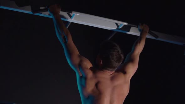 Young Man Pulls Himself Up on a Horizontal Bar