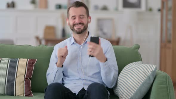 Young Man Listening Music on Smartphone at Home