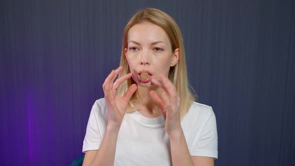 Close-up Portrait of a Blonde Girl Who Is in the Studio on a Blue Background, She Has a Cork in Her