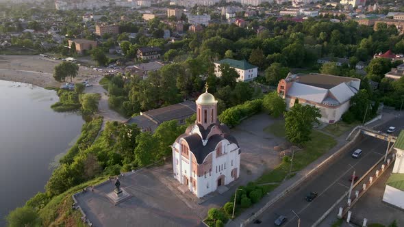 The Camera Circles Around a Small Church on the River Bank in a Small European City