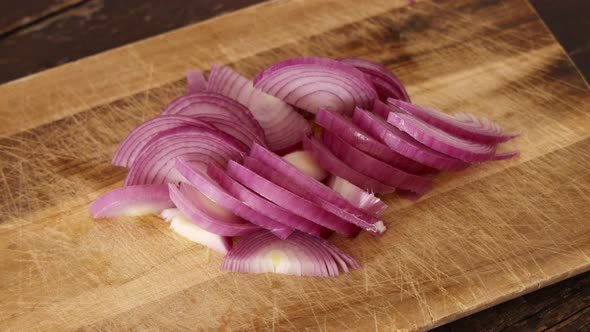 Woman's hands take chopped fresh onion from a wooden board close up