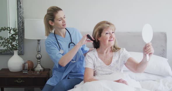 Female health worker brushing hair of senior woman at home