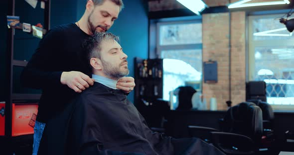 Brutal Male Barber is Putting a Paper Collar Around His Neck