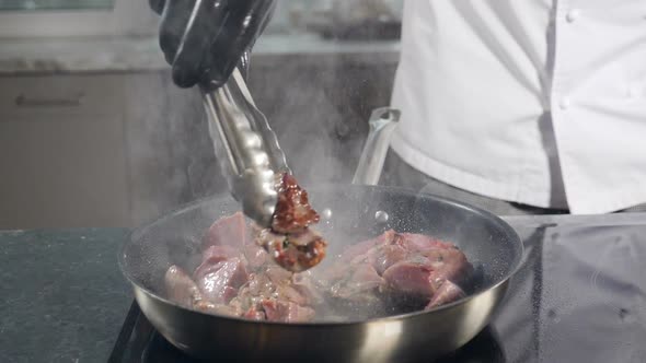 Chef Cooking Meat on Frying Pan with Splashes in Slow Motion