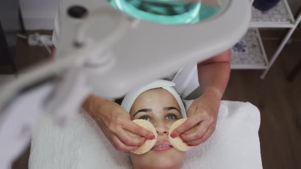 Caucasian woman lying back while beautician gives her a facial