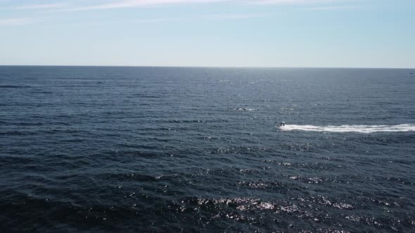 People are Playing a Water Bike in the Sea Leaving Abstract White Footprints on the Water