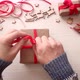 Man's hands wrap christmas present in craft paper with red ribbon and berries. - VideoHive Item for Sale