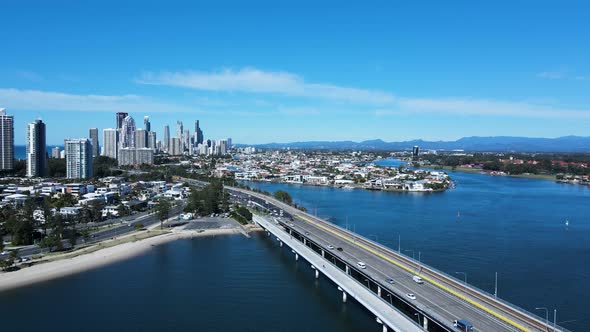 Busy urban road network and bridge spanning across a large body of water leading to a metropolitan s