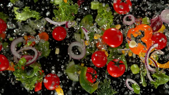 Super Slow Motion Shot of Flying Cuts of Colorful Vegetables and Water Drops on Black at 1000Fps