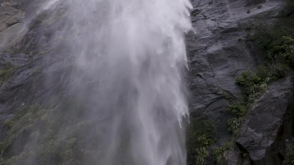 Slow motion shot from underneath a waterfall from the back of a boat. Milford Sound, New Zealand.