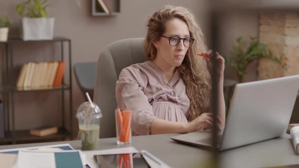 Pregnant Woman Eating Carrots in Office