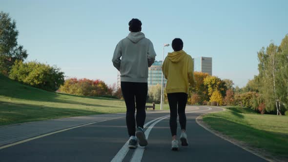 Man and Woman Running on a Track at the City Park in Sunny Autumn Morning