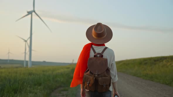 Young tourist with a red scarf near a farm with alternative energy windmills