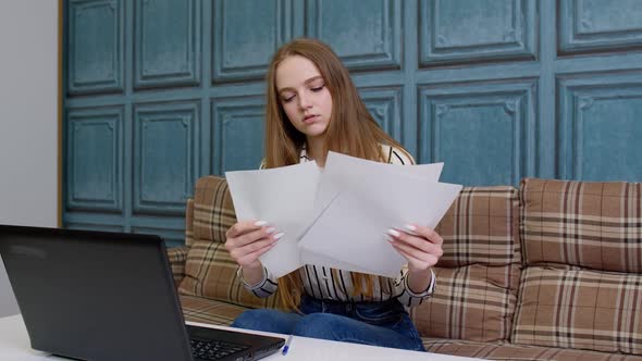 Woman Sittingat Home Looking at Documents Analyzes Data Checks Papers Working on Laptop Computer