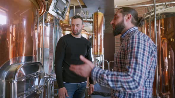 Confident Successful Pub Owner Talking with Expert Brewer Standing in Brewery Indoors