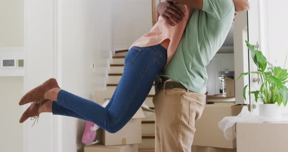 Happy biracial couple hugging with joy in new house