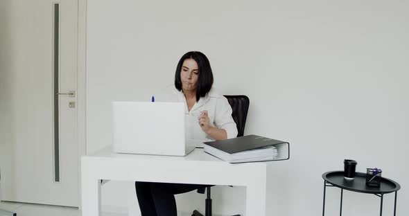 Lecturer Chatting on Laptop During Learning and Taking Off Glasses in the Office