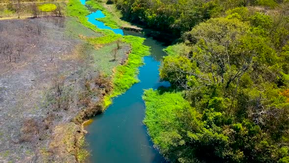 Cinematic aerial shot flying over a small colorful river