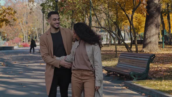 Joyful Hispanic Couple Cuddle Walking in Autumn Park Girl and Guy Holding Hands Lovers Embrace Laugh