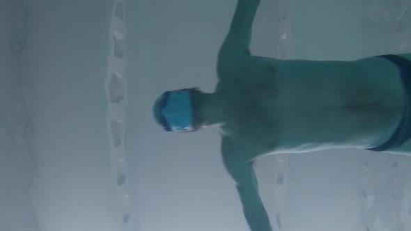 A Man Swims in the Pool in a Protective Medical Mask