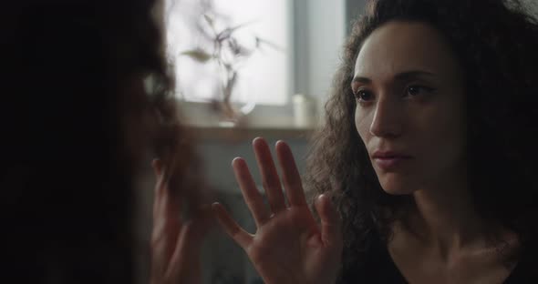 Woman reaching out hand in front of mirror