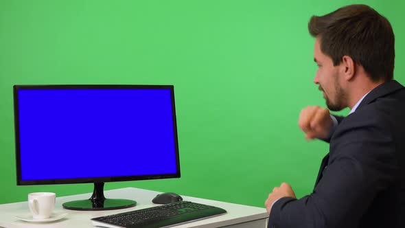 A Young Businessman Sits in Front of a Computer with Blue Screen and Dances - Green Screen Studio