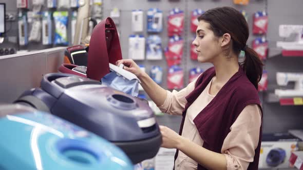 Female Costumer Choosing Vacuum Cleaner in Appliance Store