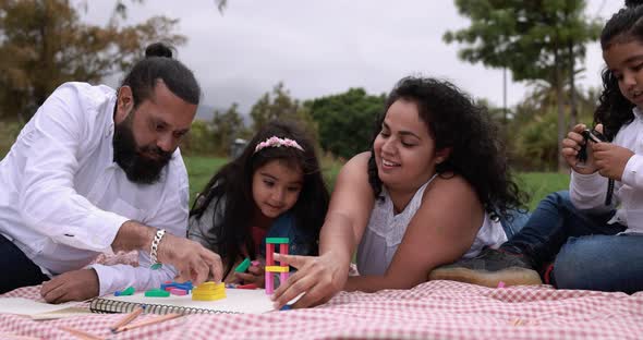 Indian parents having fun at city park playing with wood toys with their children