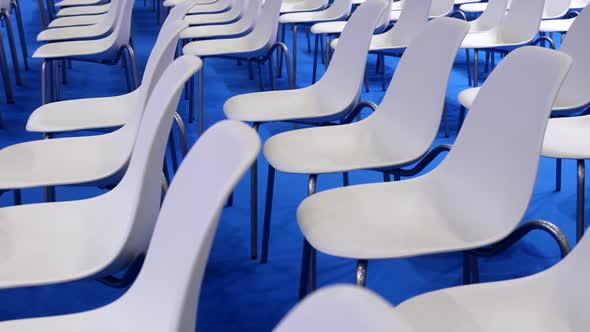 Empty White Chairs on a Blue Background in a Row