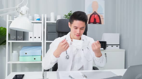 Portrait of Asian male doctor remove protective face mask in hospital.