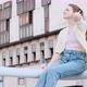 Young Woman Sits on Balcony on Industrial Building Background and Corrects Her Hair - VideoHive Item for Sale