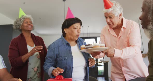 Happy senior diverse people at birthday party with cake and gifts at retirement home