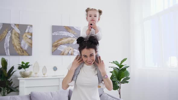 Woman with Funny Hairstyle Holding on Shoulders Her Satisfied Little Daughter