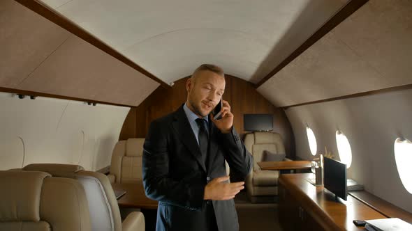 Businessman Talking on Cell Phone Indoor of Private Jet Cabin