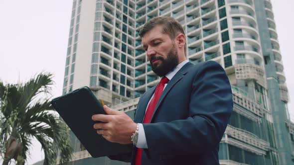 Portrait of a Serious Business Man Bearded Businessman in an Expensive Suit in a Red Tie Working on