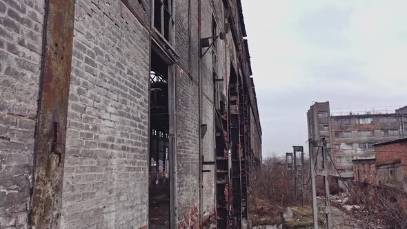 Former plant building with damaged brick walls and metal structures covered with moss