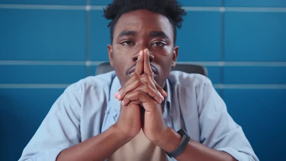 Young African American Man Freelancer Looking at Camera Sits at Desk in Office