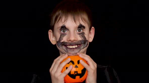 portrait of a cheerful caucasian boy 7-8 years old with a grim zombie monster holding a pumpkin bask