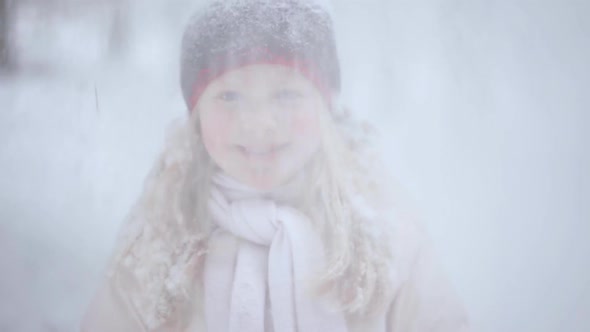 Portrait of a Beautiful Blonde Girl in the Winter Forest with Falling Snow